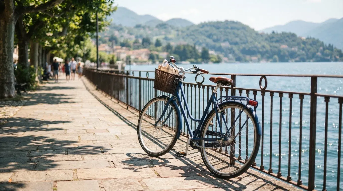 Ein Fahrrad lehnt an einem Geländer einer Uferpromenade an einem See im Sonnenlicht.