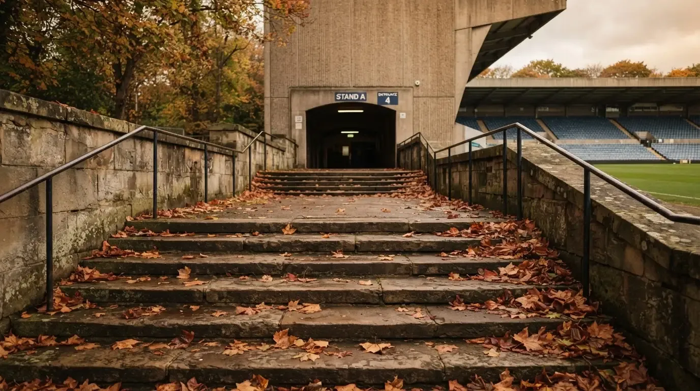 Eine breite Steintreppe führt zum Eingang einer Tribüne, Herbstlaub liegt auf den Stufen.